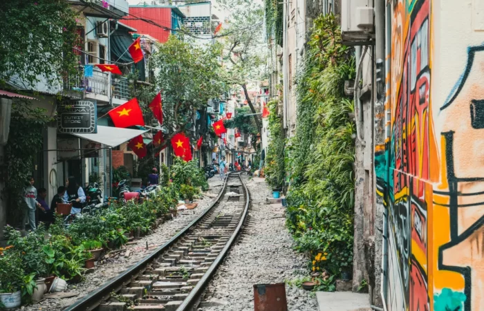 Ruelle étroite à Hanoï, avec une voie ferrée et des maisons colorées.